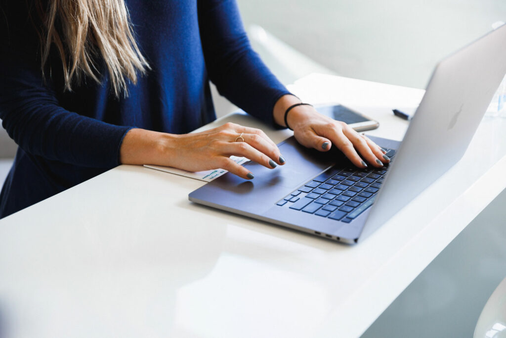 Hands typing on a laptop at a table.