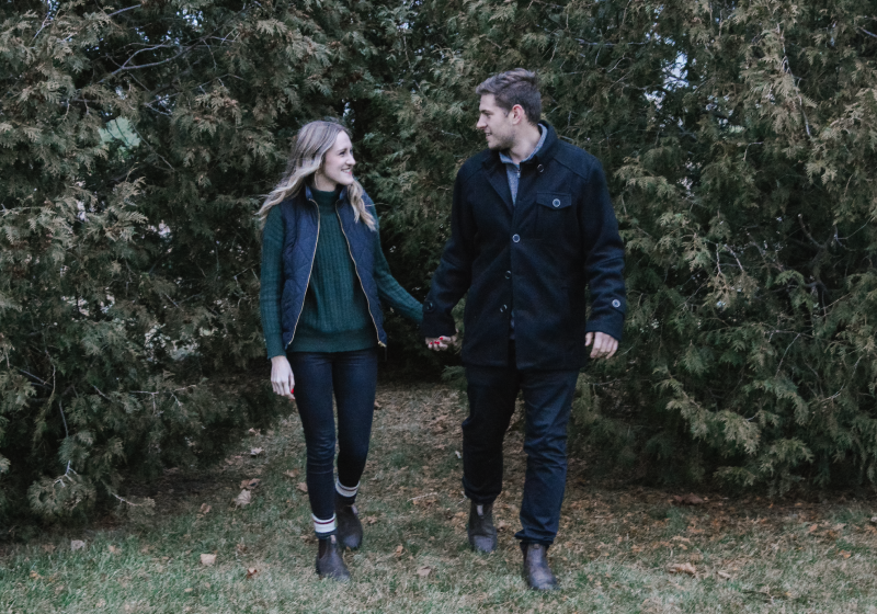 Couple walking hand in hand through forest