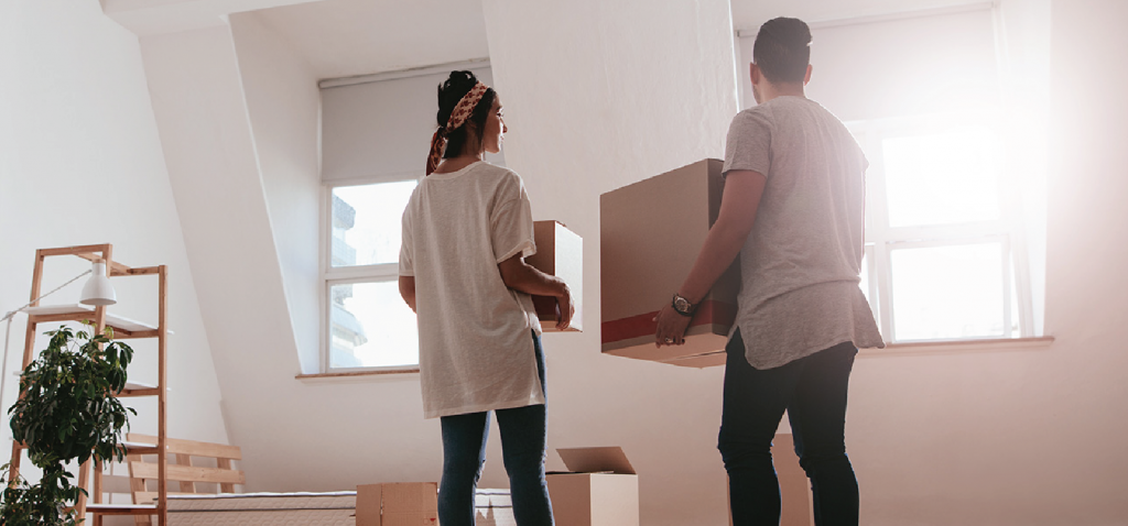 Couple holding boxes in packed-up apartment
