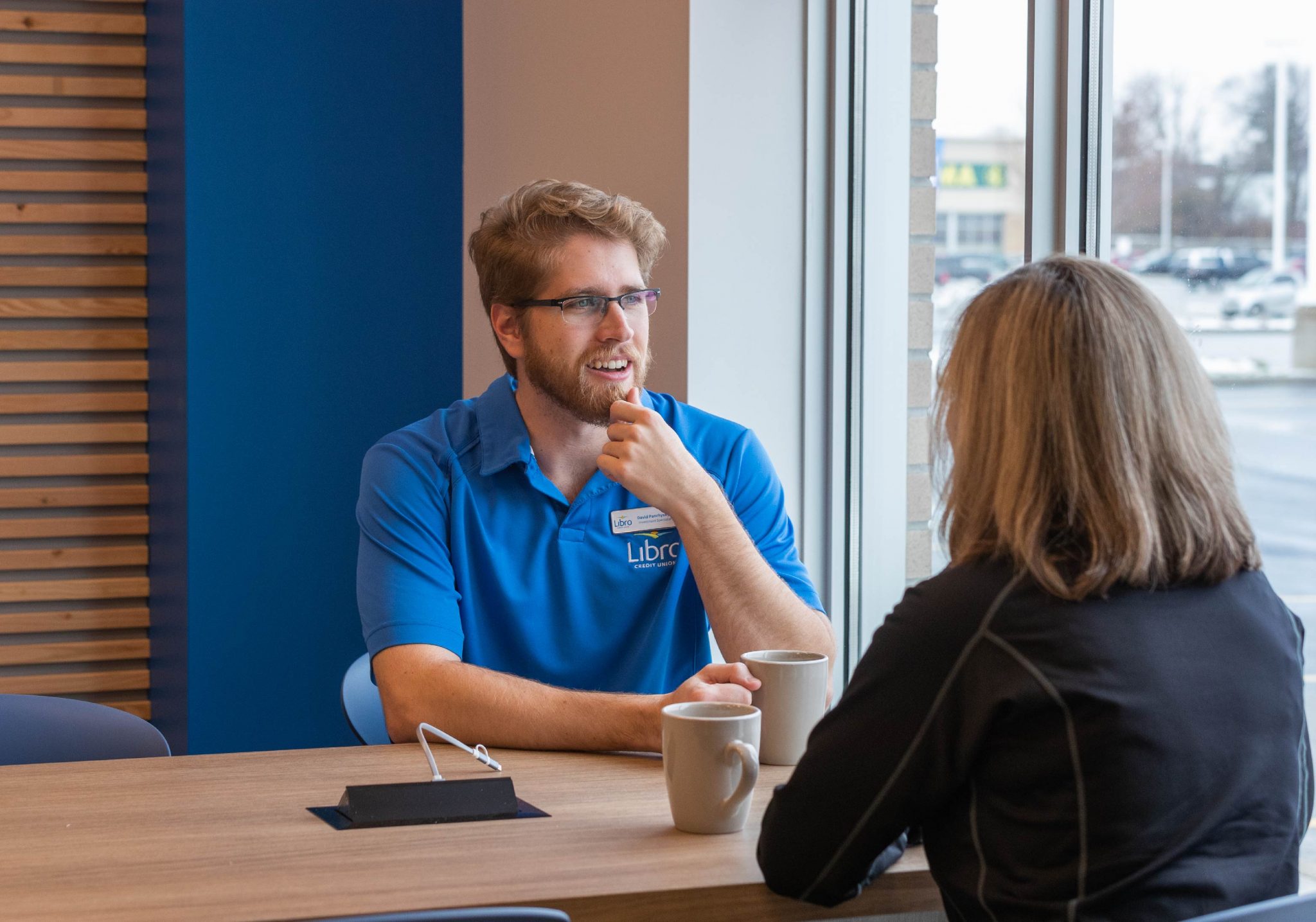 Libro staff member Dave speaking with a Member sitting at a table