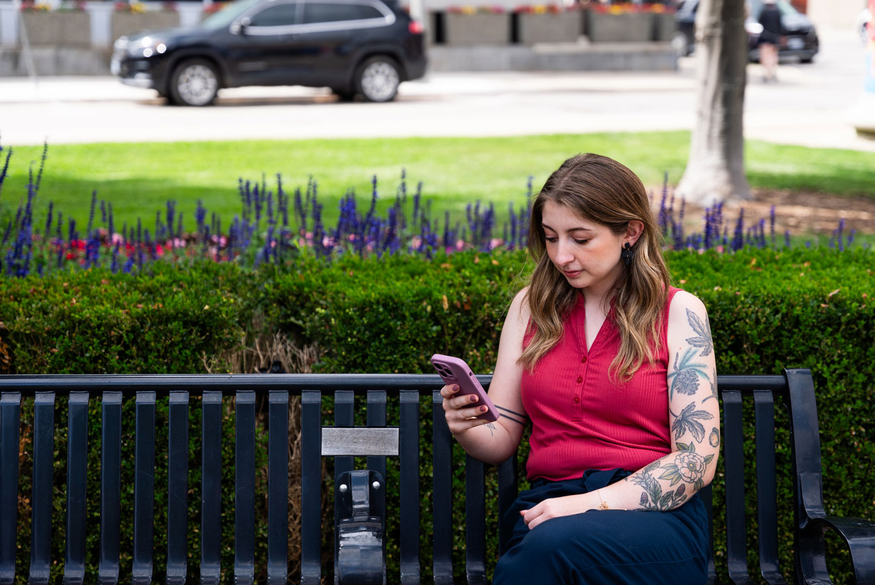 Libro Owner sitting on a bench looking at phone