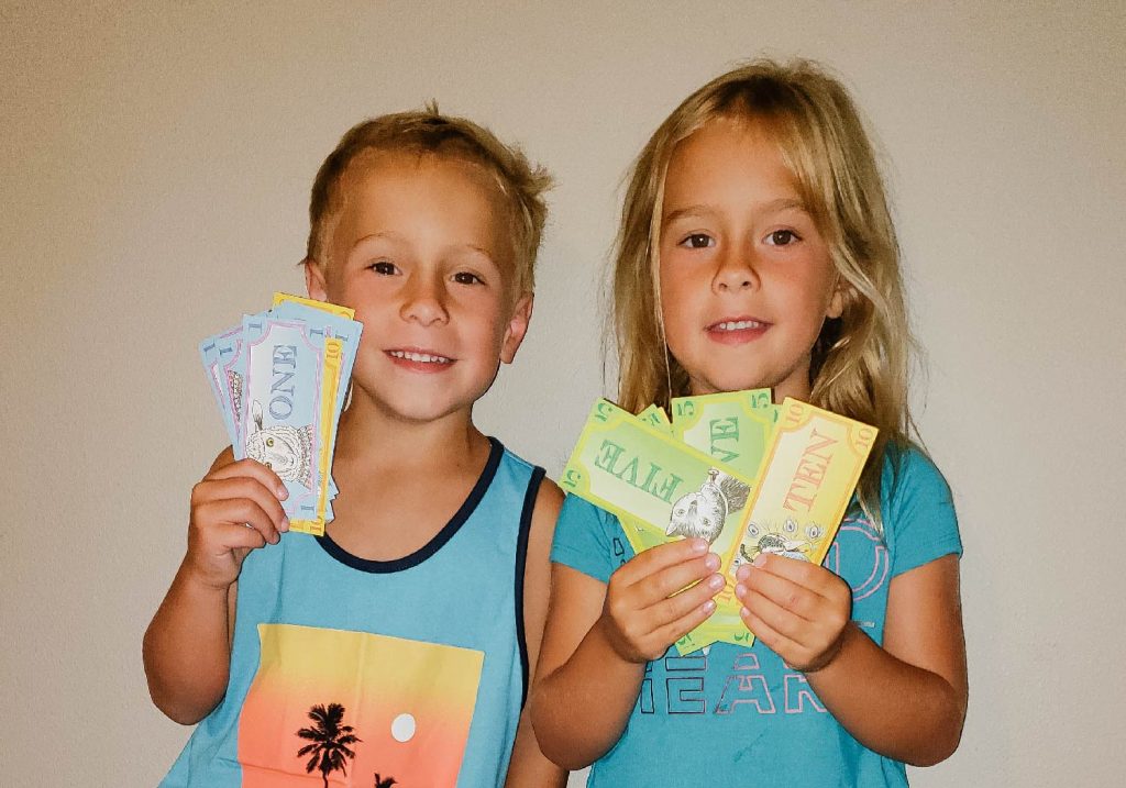 Girl and boy holding up play money