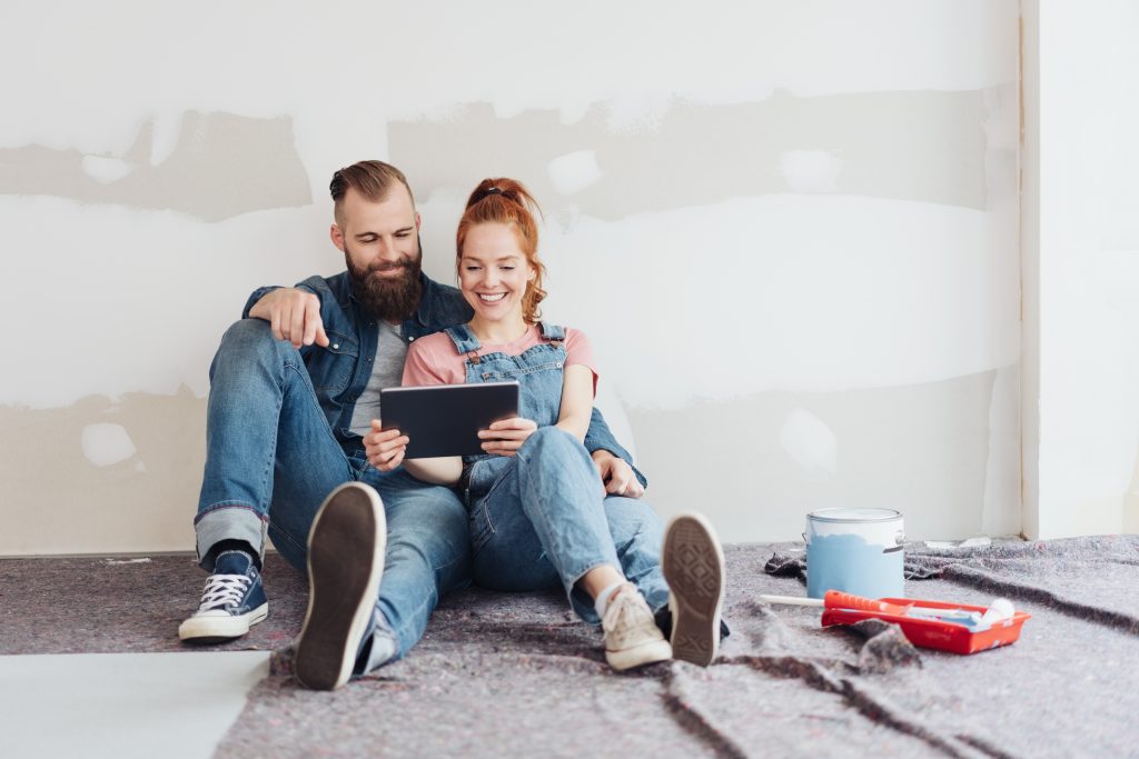 Couple sitting in renovated room looking at ipad