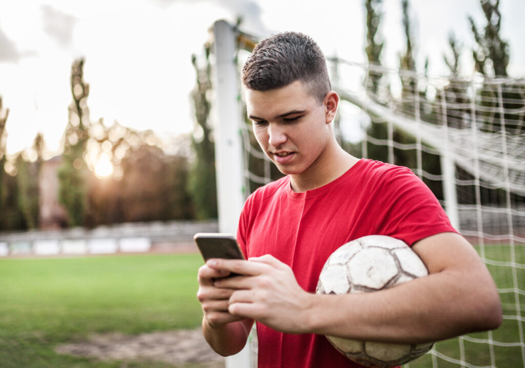 Young boy looking at phone while at soccer practice