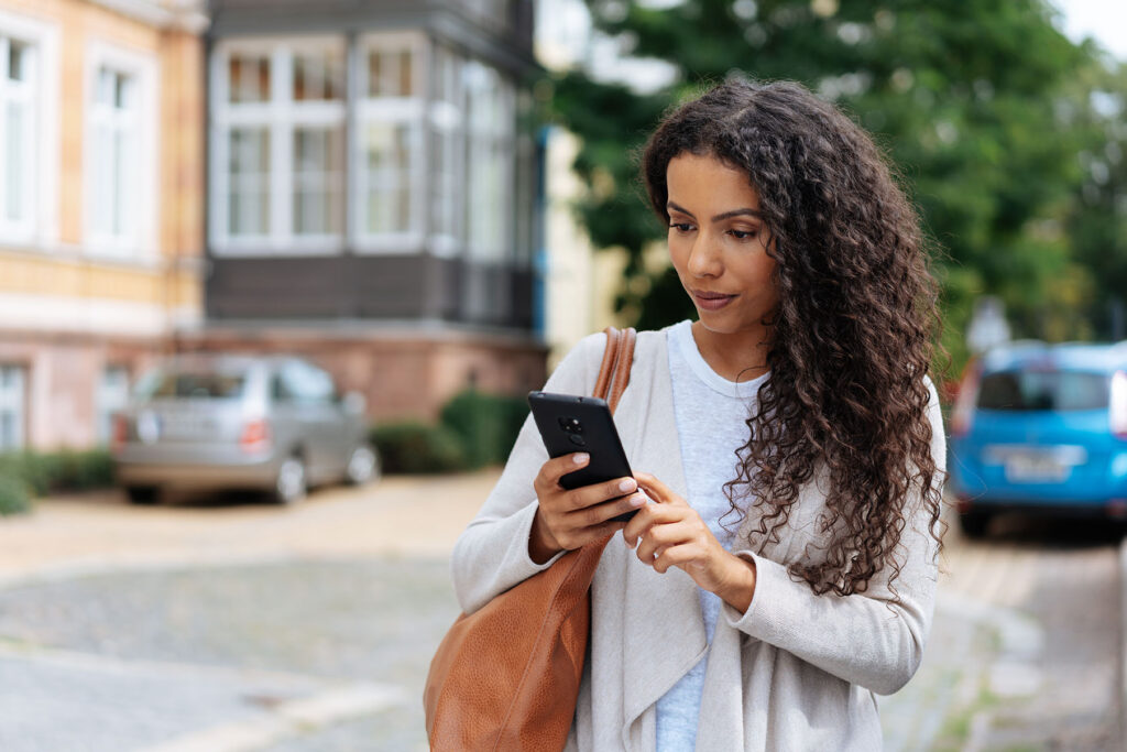 woman walking on street looking at phone