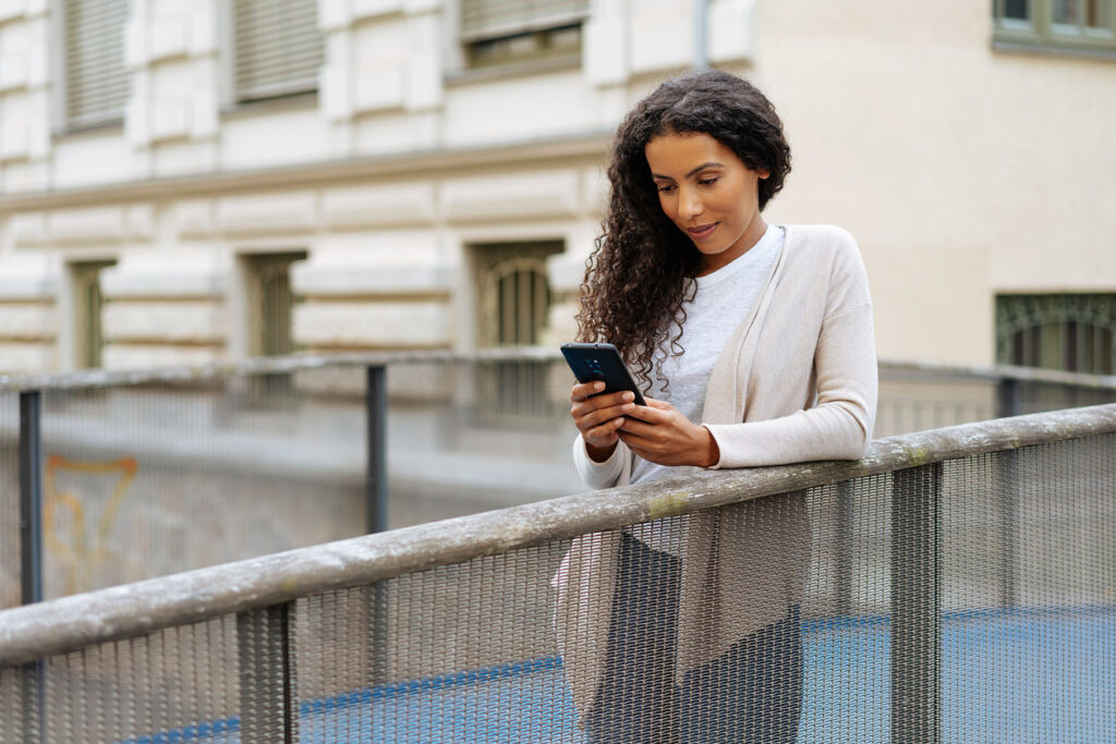 woman leaning on railing looking at phone