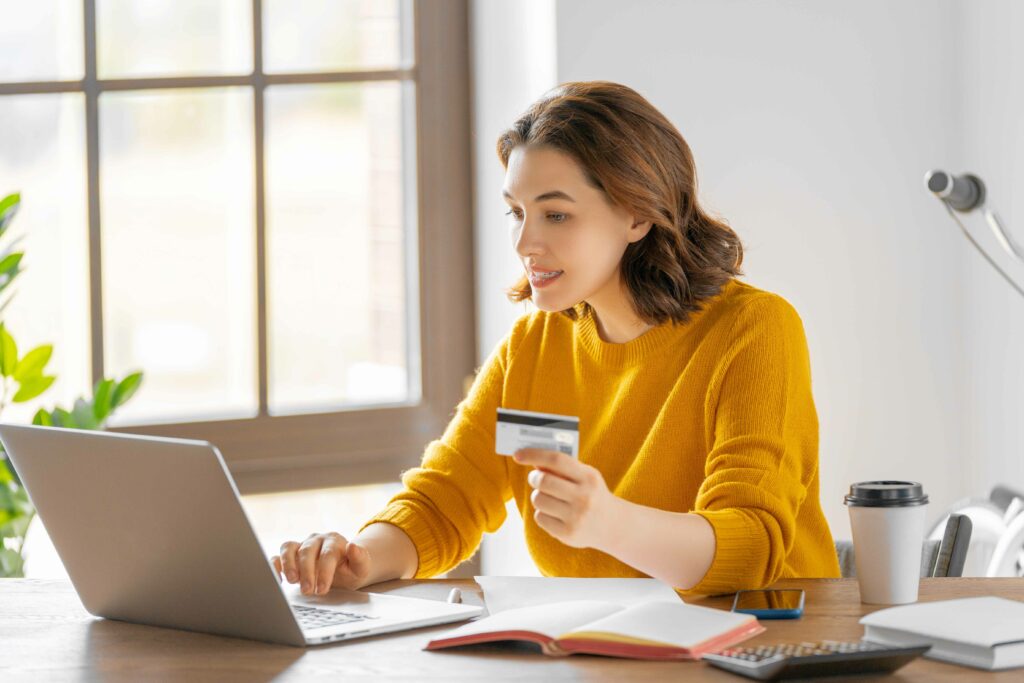Woman with credit card in hand on laptop