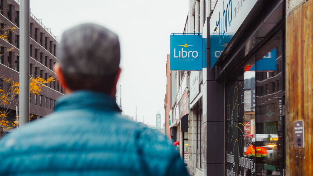 A person walking down the street toward a Libro Branch