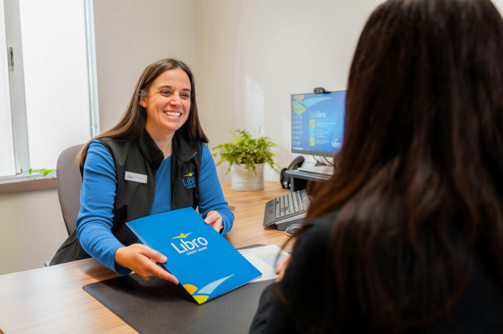 Libro Staff member sitting at a desk holding a folder with the Libro logo on it