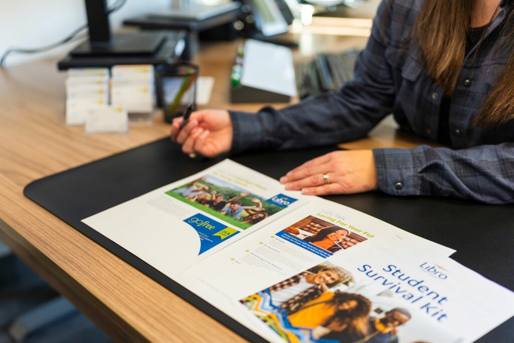 A Libro Coach sitting behind various pages of student resource materials for financial planning and education