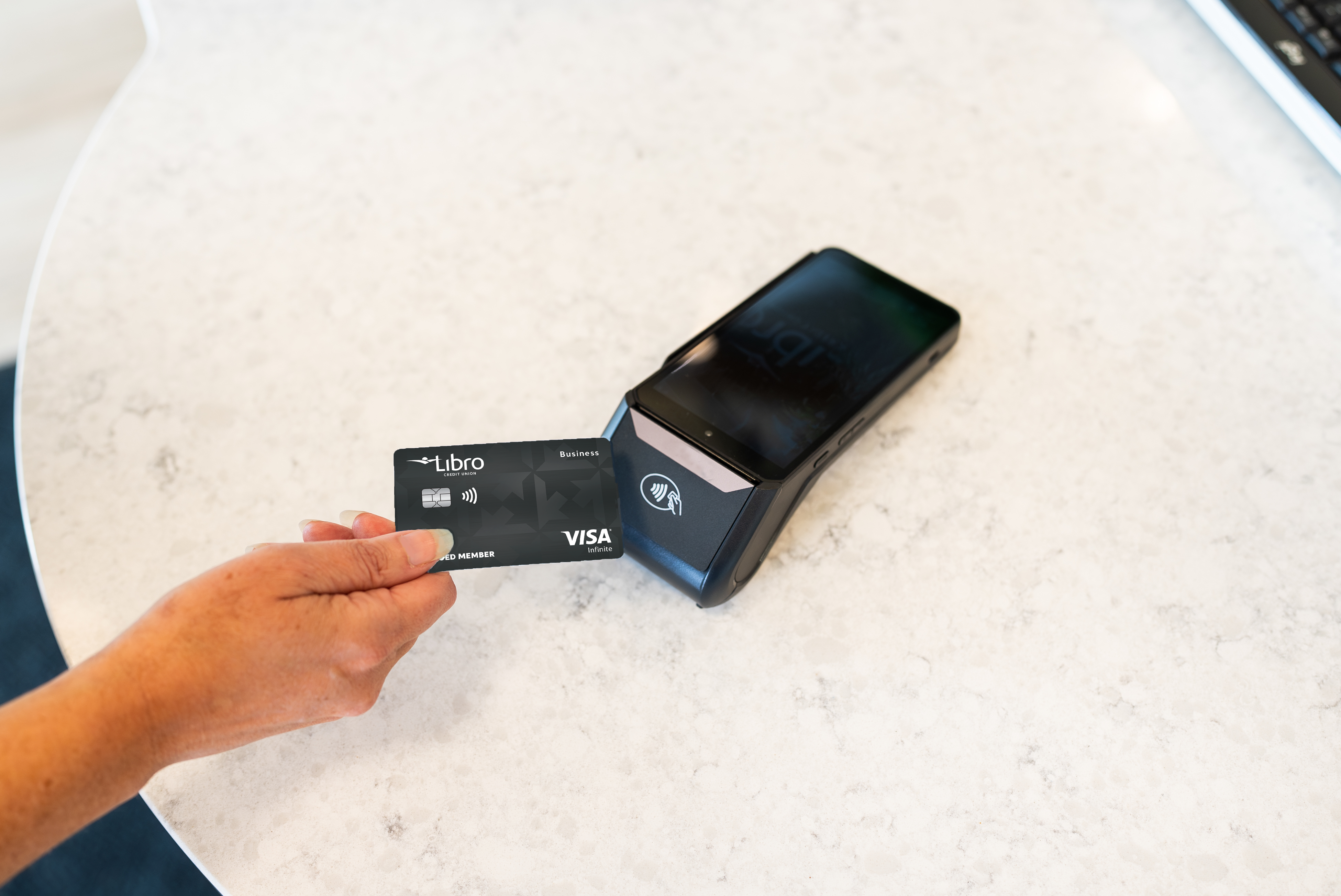 Owner holding a Libro Business Visa at a debit machine