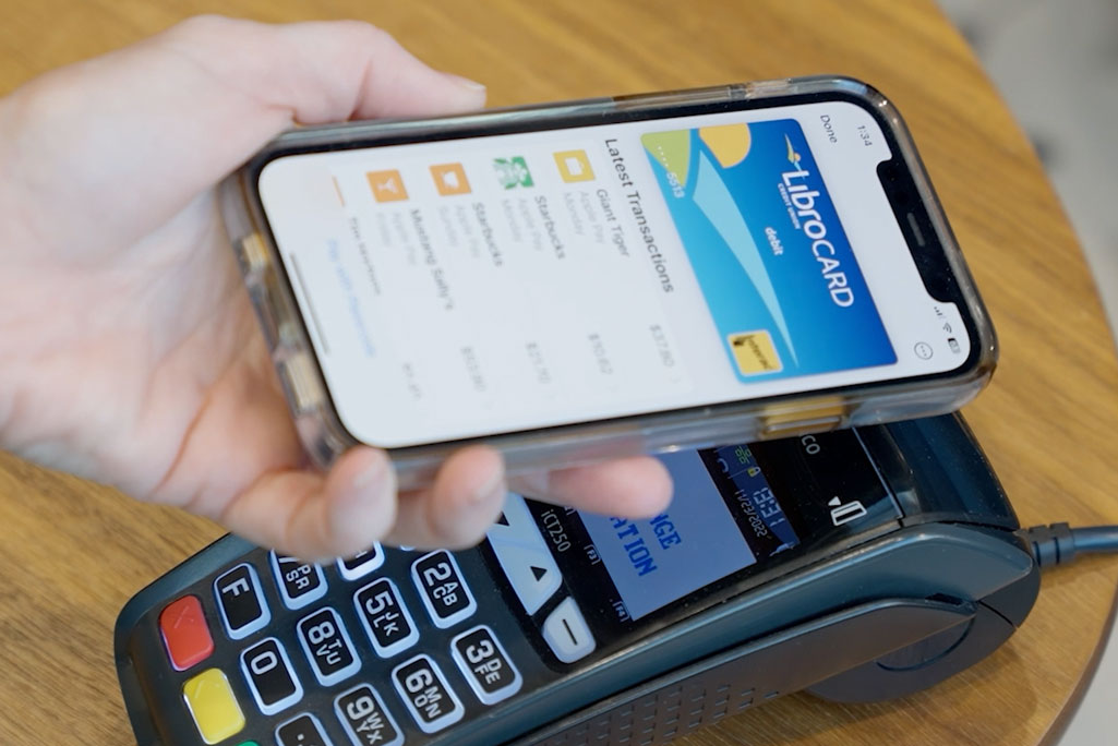 Hand holding phone using Apple Pay over POS machine