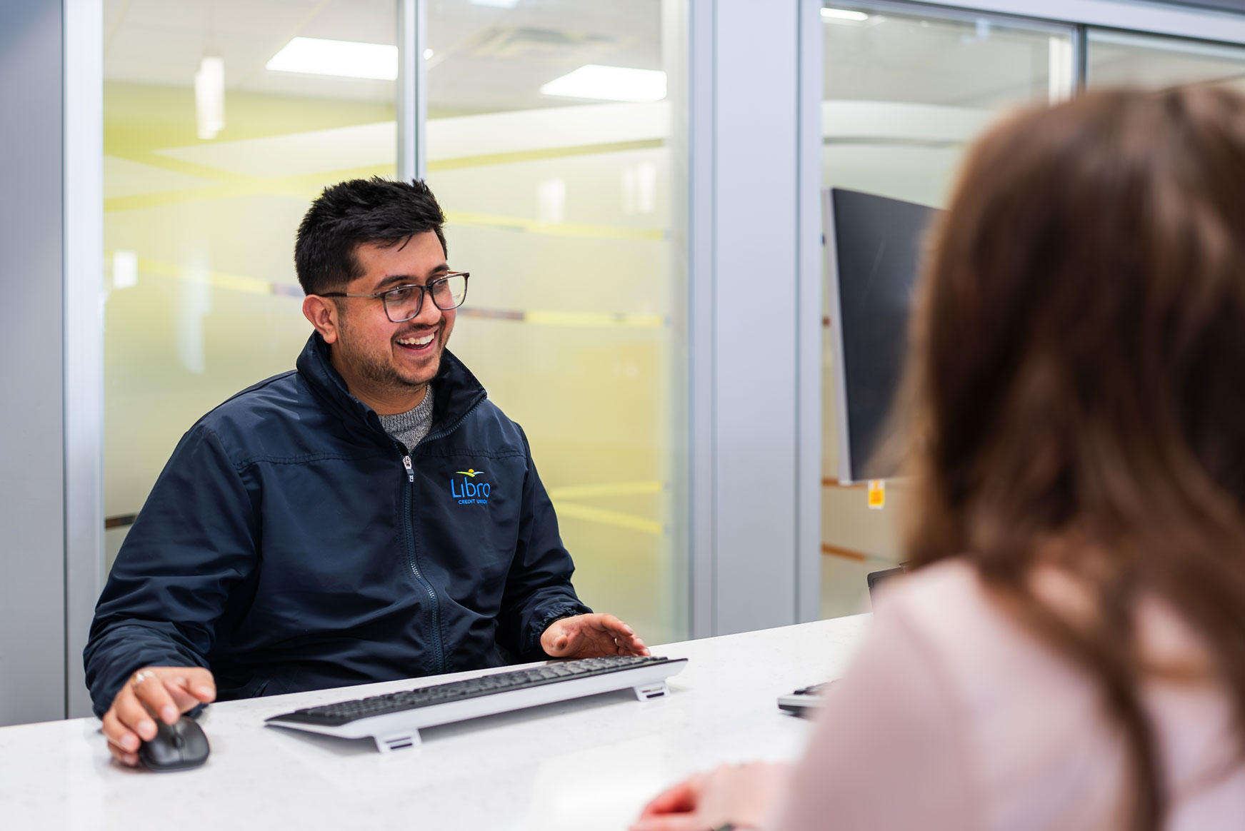 A Libro Staff sitting at a wicket talking to a Libro Owner