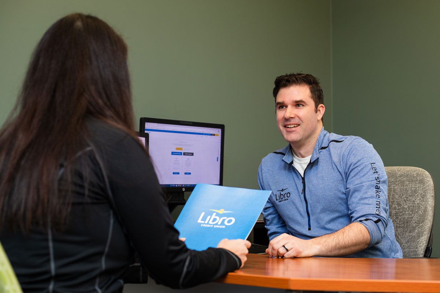 Libro Staff member talking to a Libro Owner sitting at a desk