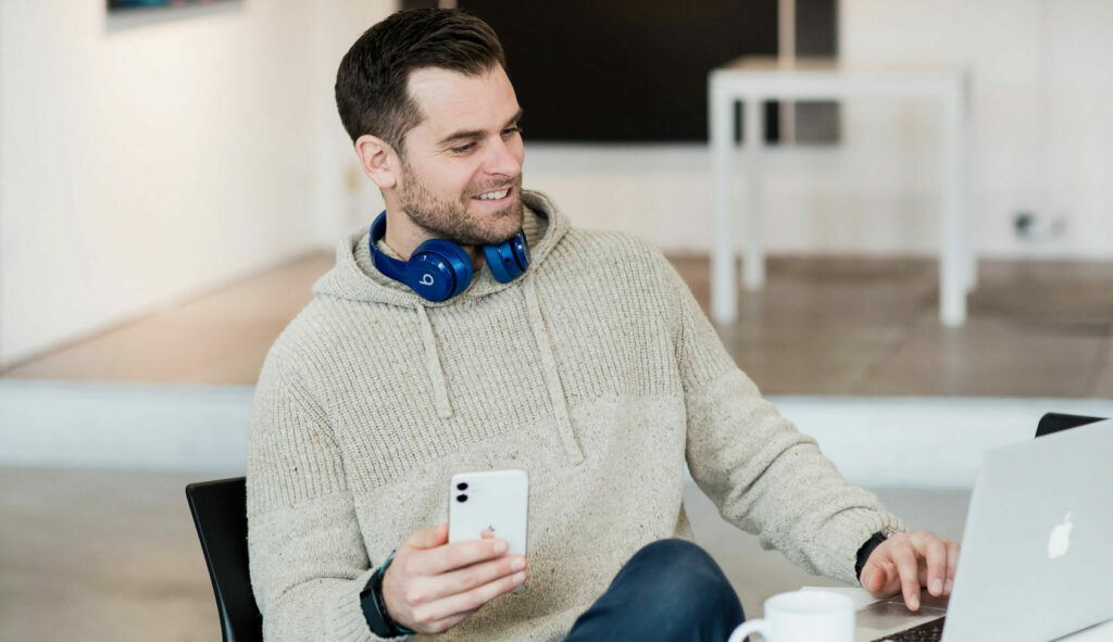 A Libro Owner holding his phone and looking at his laptop