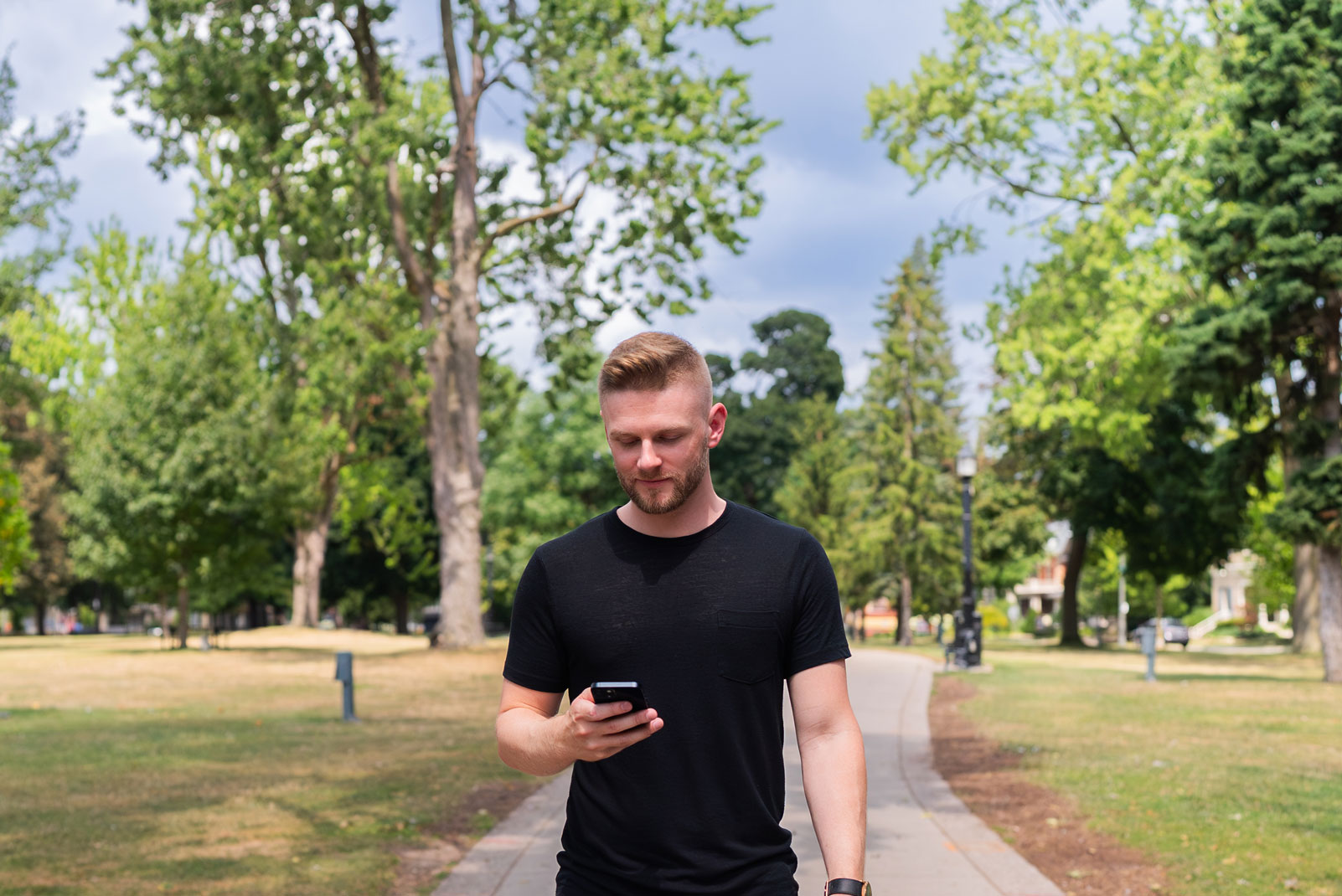 Libro Business Owner, A.J. Assisting You, walking in the park and looking at his phone