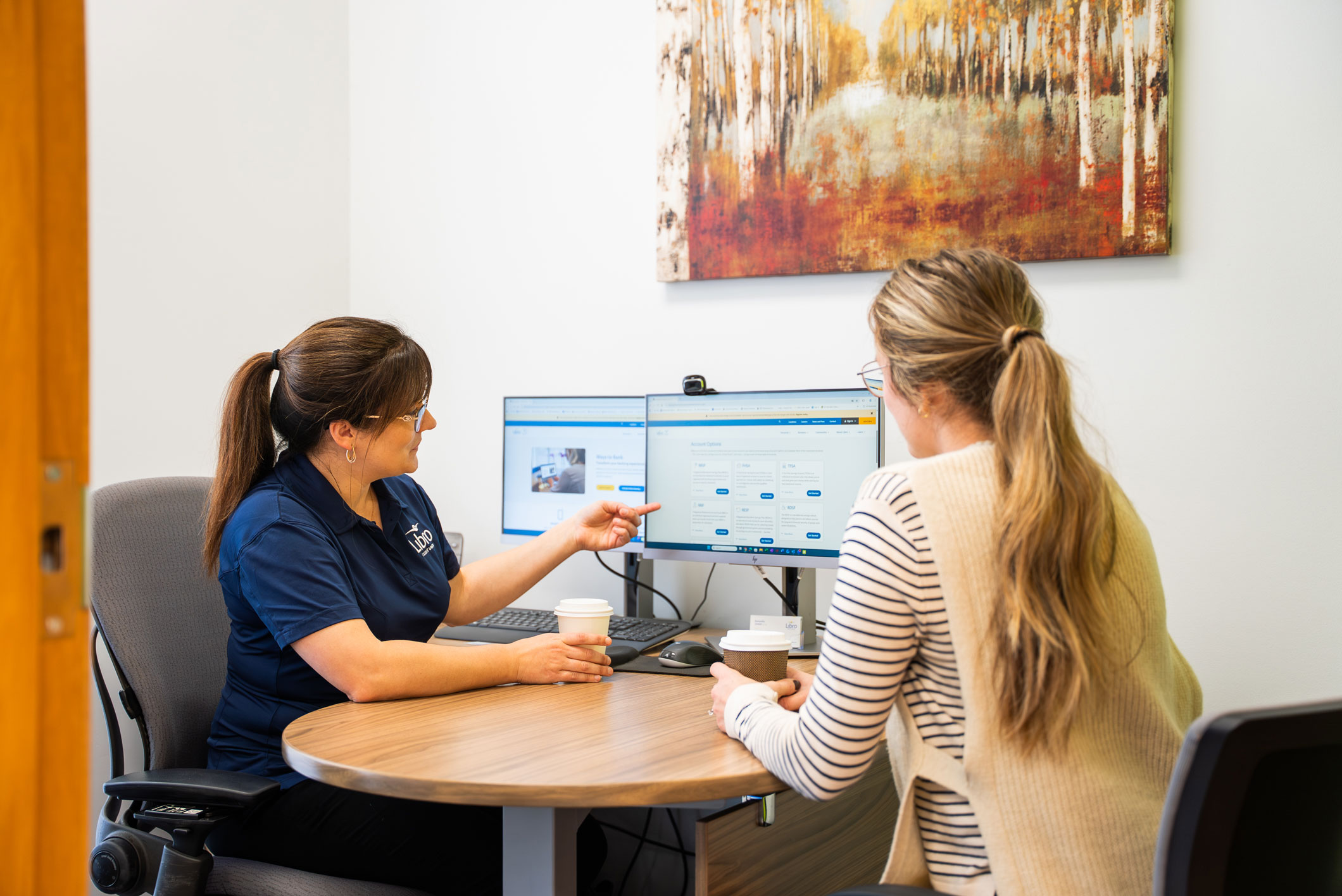 Libro Staff Amanda talking with a Libro Owner and pointing at computer