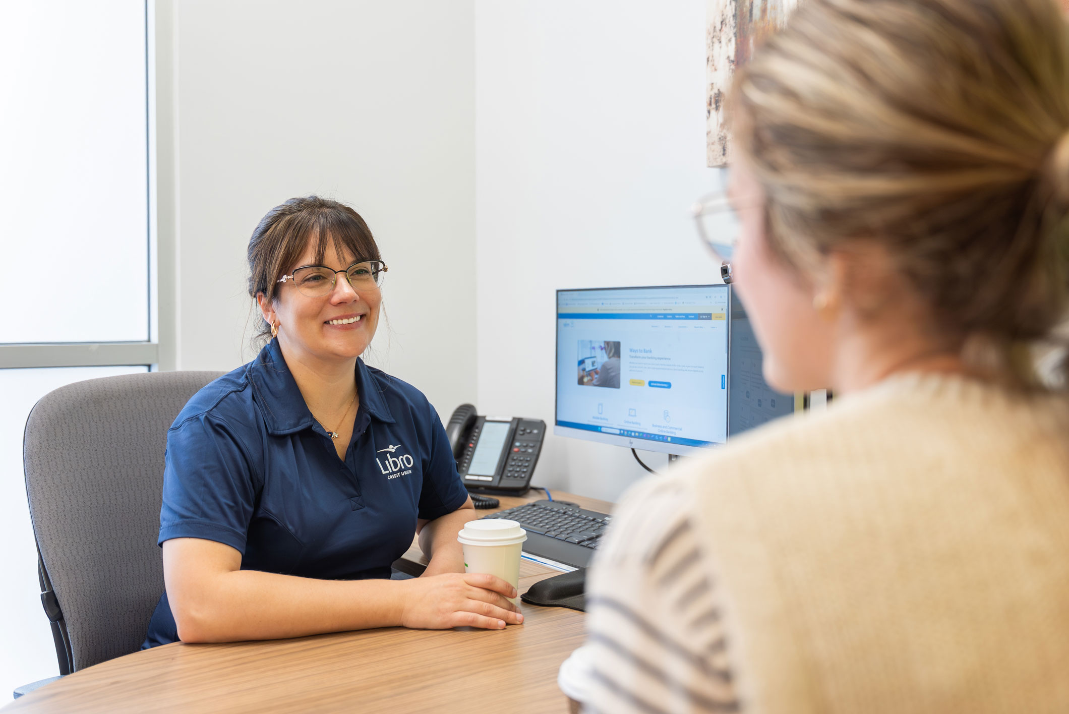 Libro Staff Amanda sitting behind a desk and smiling at a Libro Owner
